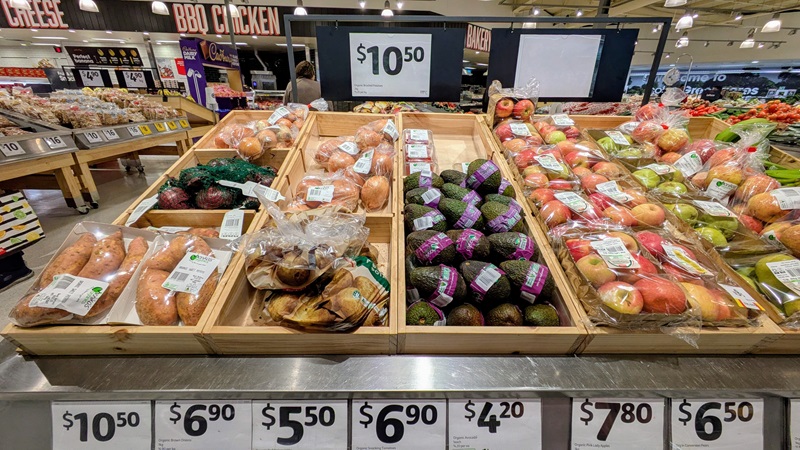 American supermarket produce section displaying various avocado varieties and price points