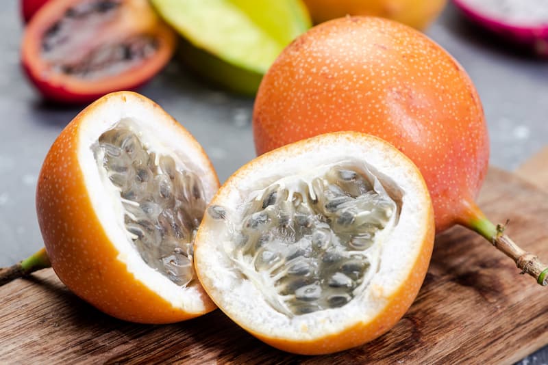 Sweet granadilla passion fruit from Kenya showing orange-brown hard shell and round shape, premium specialty variety for fresh markets