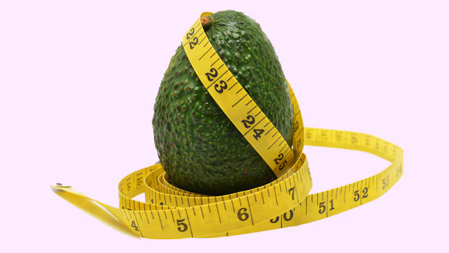 Fresh halved avocado alongside a measuring tape — exploring whether avocado helps with weight loss, belly fat reduction, or causes weight gain